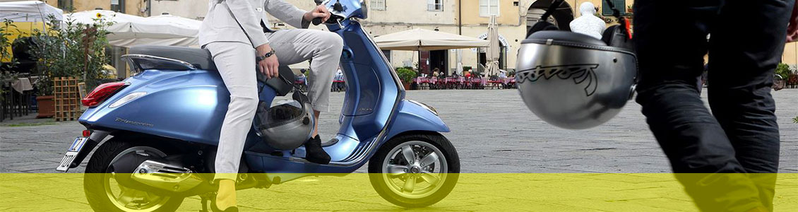 A person sitting on a blue scooter with another person walking towards them and both are holding helmets