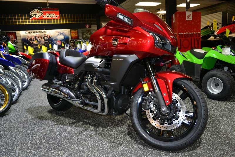 A red and black motorcycle sitting in a store with other powersport vehicles around it